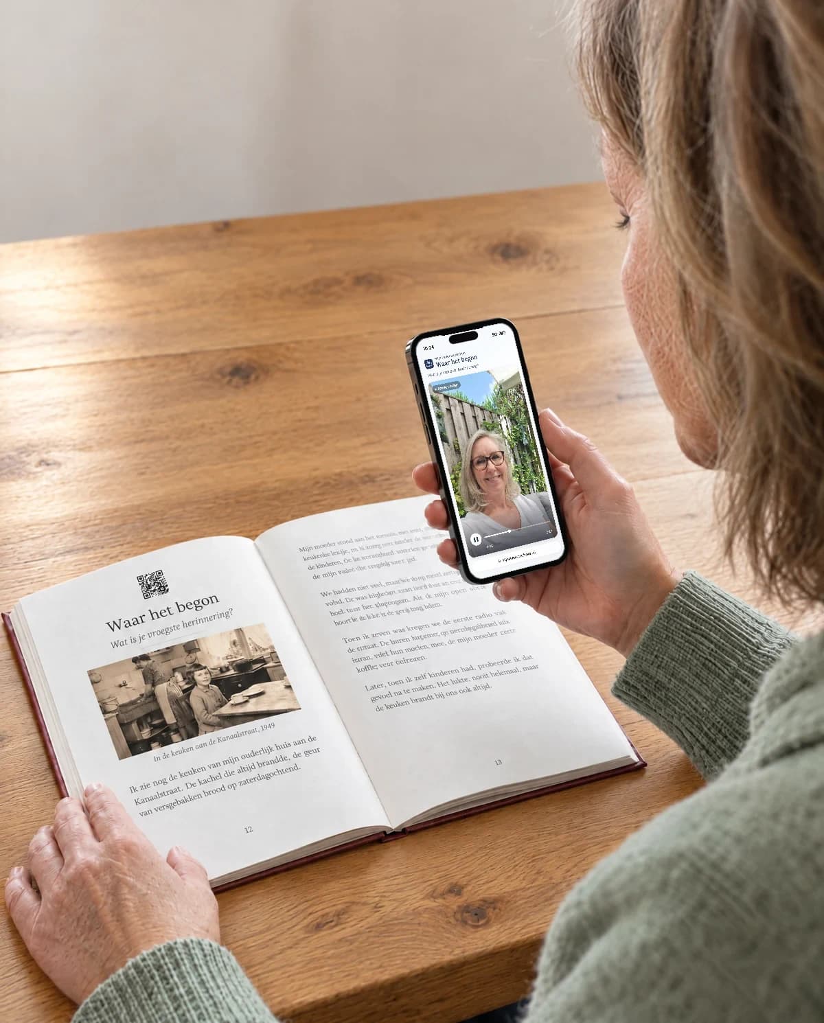 Marieke schaut auf ihrem Handy die Geschichte ihrer Mutter Annie an, das aufgeschlagene Buch liegt vor ihr auf dem Tisch.
